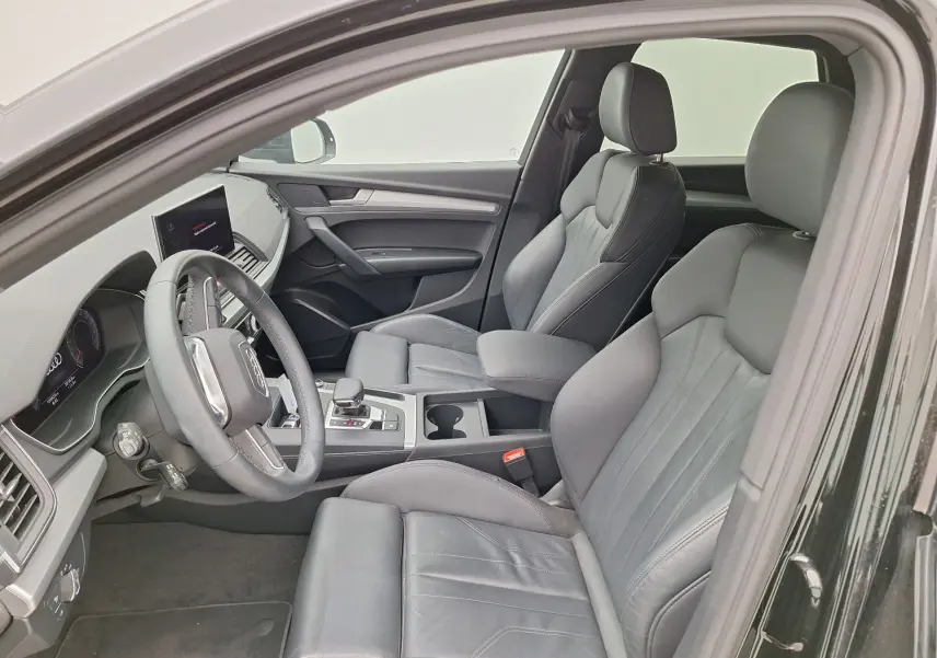 Vue intérieure côté gauche de l'Audi Q5 Business Edition S-Line noire, mettant en valeur les sièges sport en cuir et le tableau de bord digital.