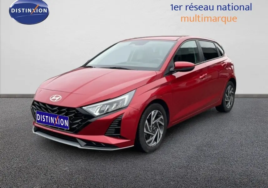 Vue 3/4 avant d'une Hyundai i20 1.0 TGDI rouge dragon métal avec jantes alliage et calandre noire distinctive.