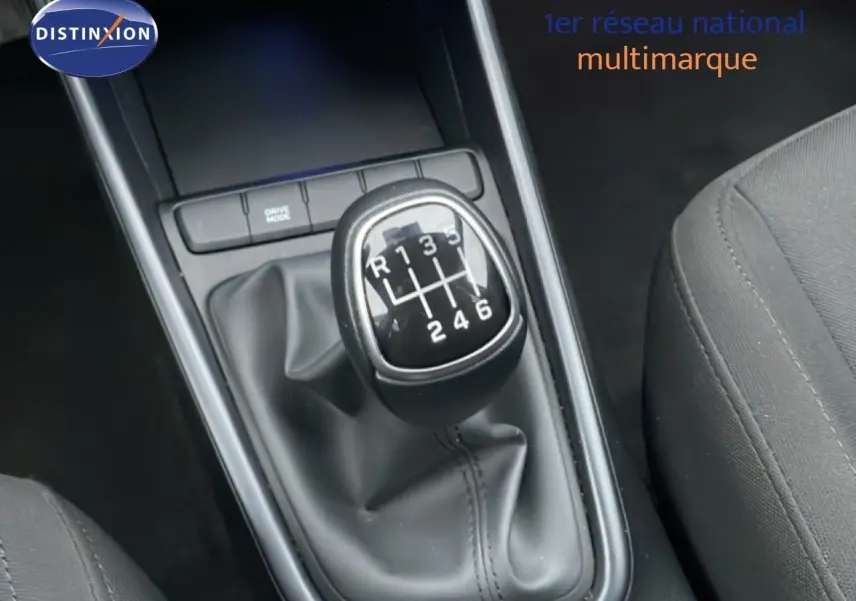 Gros plan sur le levier de vitesses manuel noir de la Hyundai i20 2025, intérieur tissu gris visible côté droit.