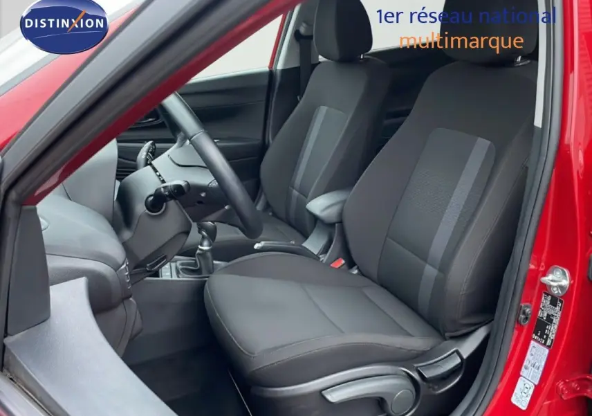 Vue intérieure côté conducteur de la Hyundai i20 rouge Dragon Metal, montrant les sièges et la console centrale.