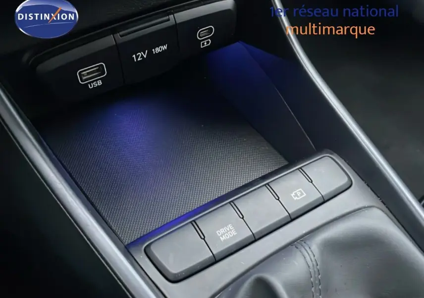 Gros plan sur la console centrale noire de la Hyundai i20 2025, avec boutons Drive Mode et prise USB visible.