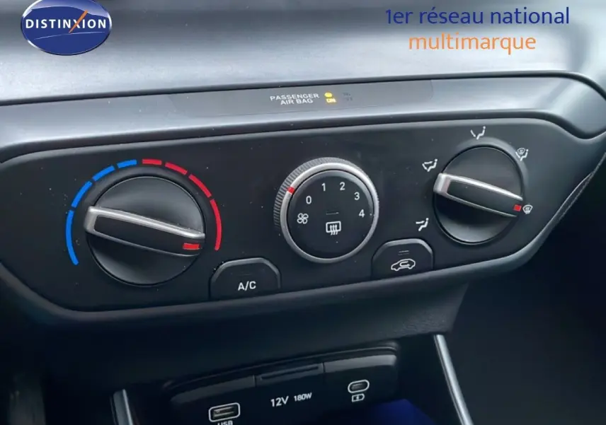 Vue rapprochée du tableau de bord de la Hyundai i20 2025 rouge Dragon Metal, montrant les commandes de climatisation et ports USB.