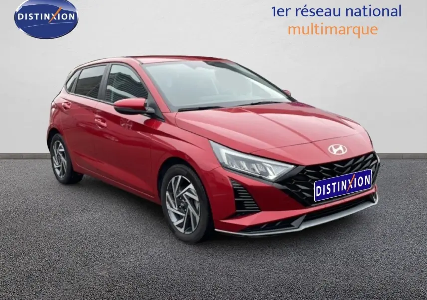 Vue 3/4 avant d'une Hyundai i20 2025 rouge Dragon Metal avec calandre noire et jantes alliage.
