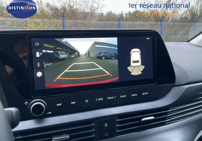 Écran tactile intérieur montrant la caméra de recul de la Hyundai i20 rouge Dragon Metal, vue du tableau de bord côté conducteur.