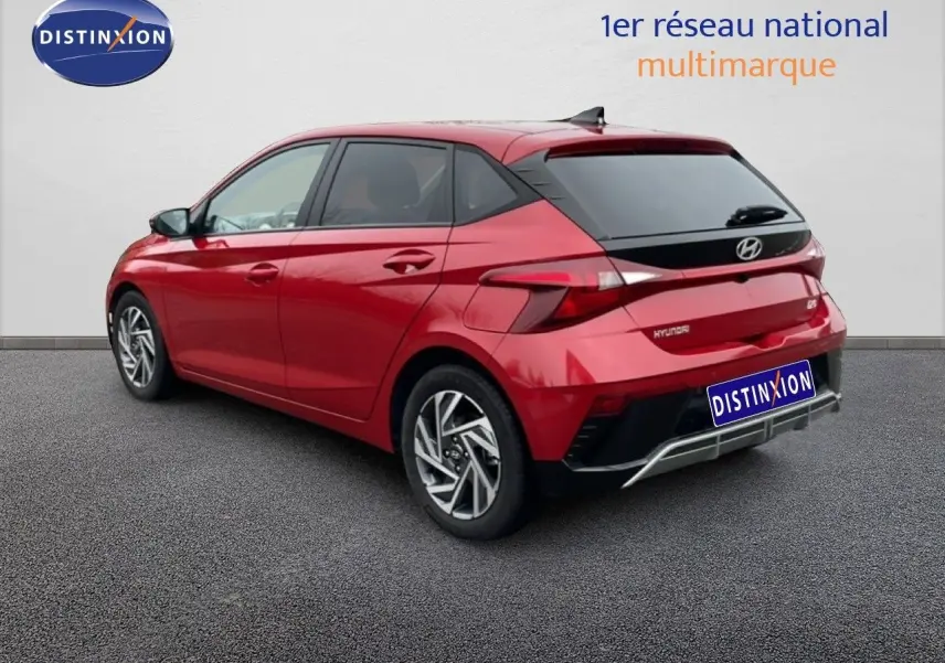 Vue 3/4 arrière droite d'une Hyundai i20 2025 rouge Dragon Metal avec jantes alliage et feux LED distinctifs.