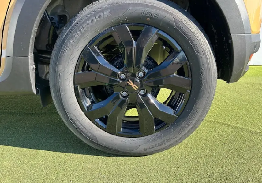 Gros plan sur la roue avant droite noire brillante du Dacia Sandero Stepway Beige Safari avec jante aluminium 16 pouces.