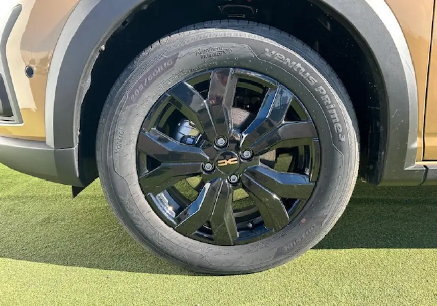 Gros plan sur la roue avant droite noire brillante du Dacia Sandero Stepway beige Safari avec jante aluminium 16 pouces.