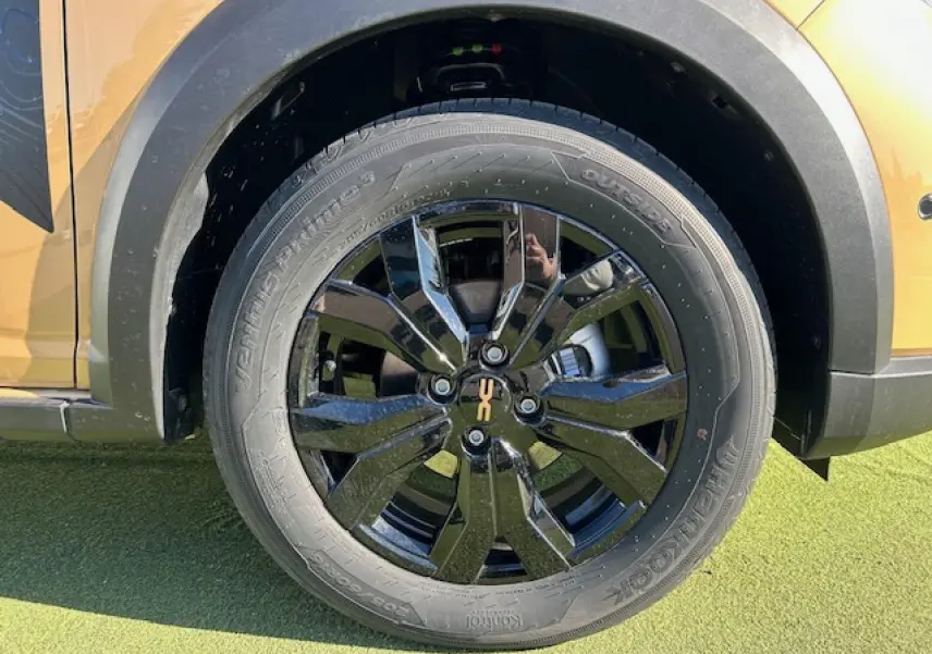 Gros plan sur la roue arrière droite noire brillante avec logo Stepway sur un Dacia Sandero beige Safari.