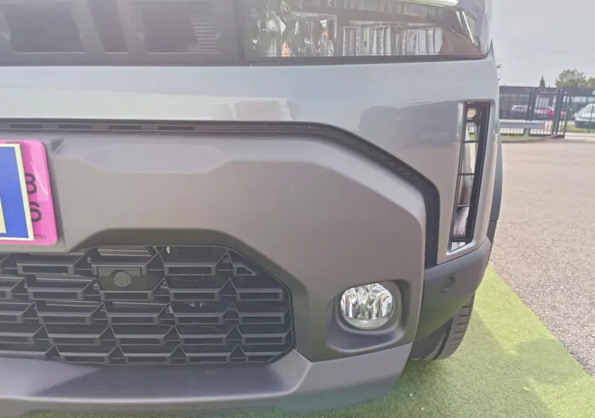 Gros plan sur l’avant droit du Dacia Duster gris schiste, mettant en valeur la calandre et le projecteur antibrouillard.