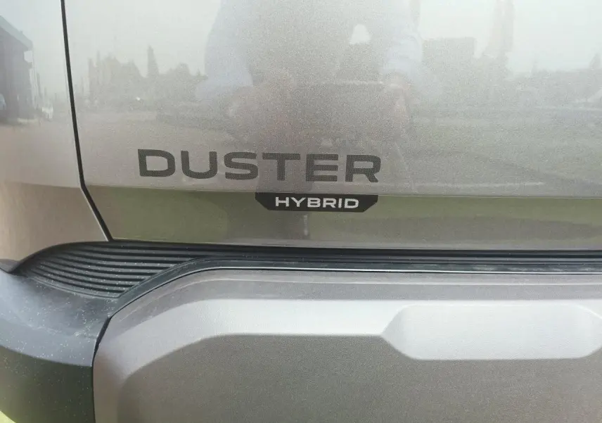 Gros plan arrière sur le logo Duster et l’inscription Hybrid du SUV gris schiste métallisé.