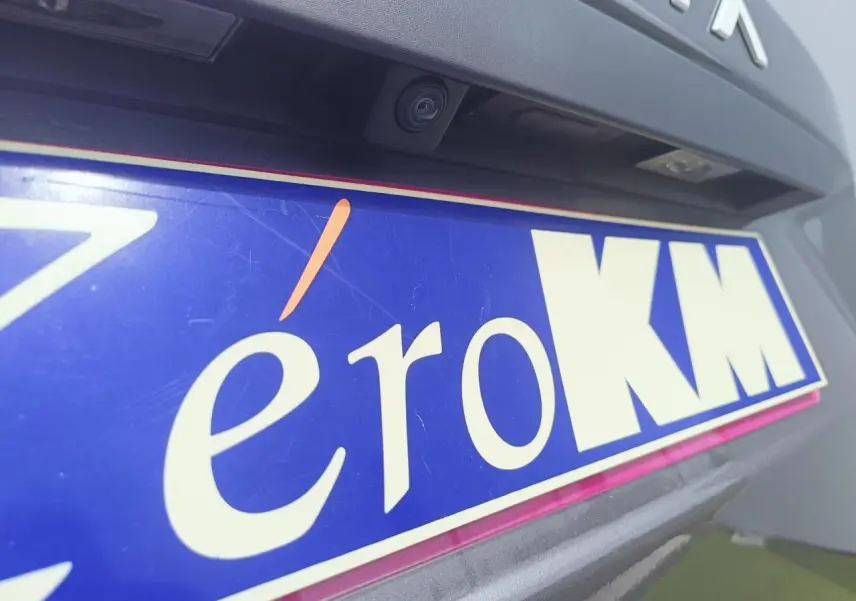 Gros plan sur la caméra de recul et la plaque d'immatriculation bleue d'un Dacia Duster gris schiste métal, arrière du véhicule.