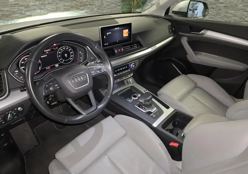 Vue intérieure côté conducteur de l'Audi Q5 gris avec sellerie cuir gris Roche et tableau de bord moderne.