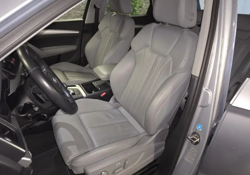 Vue intérieure côté conducteur de l'Audi Q5 gris, mettant en valeur la sellerie cuir Gris Roche et les sièges avant massants.
