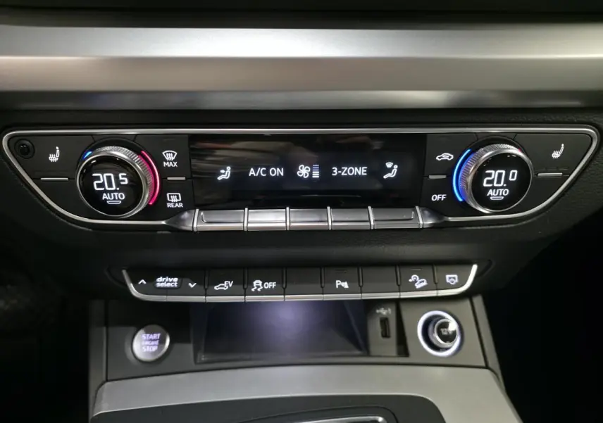 Tableau de bord de l'Audi Q5 gris, vue centrée sur la console de climatisation automatique 3 zones avec commandes digitales.