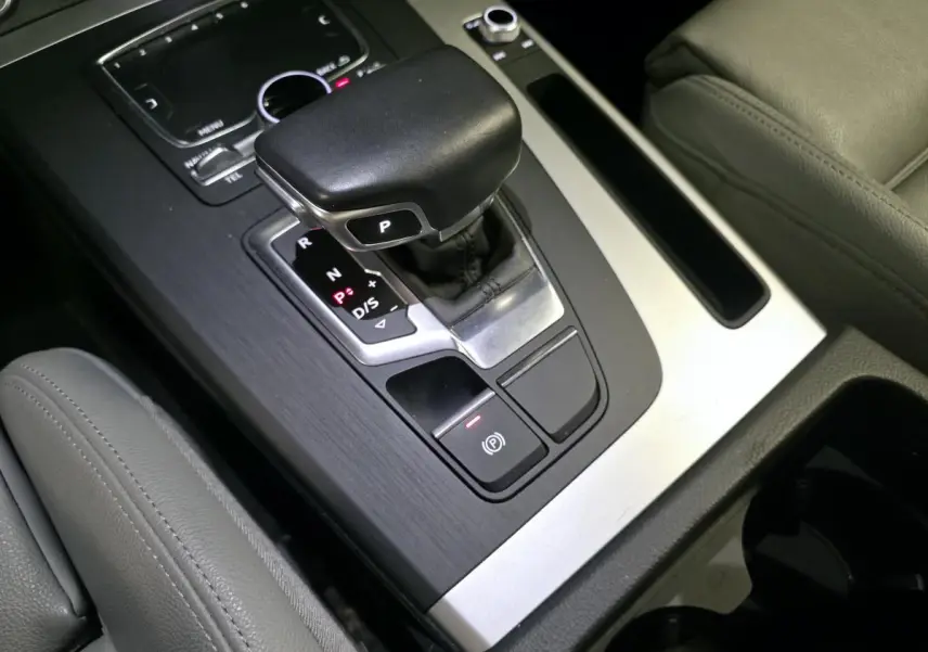 Gros plan sur la console centrale avec levier de vitesse automatique et sellerie cuir gris dans un Audi Q5 hybride rechargeable.