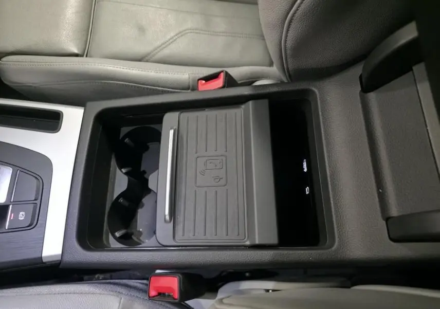 Vue plongeante sur la console centrale noire et grise de l'Audi Q5 S line 2019 avec chargeur à induction et porte-gobelets.