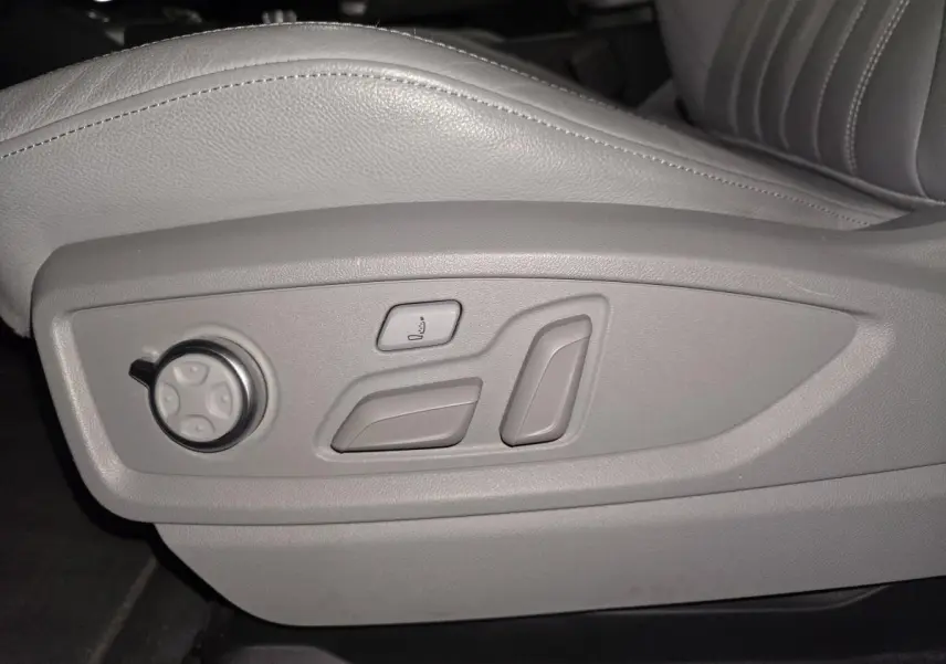 Gros plan sur les commandes électriques grises du siège avant conducteur en cuir gris de l'Audi Q5 S line.