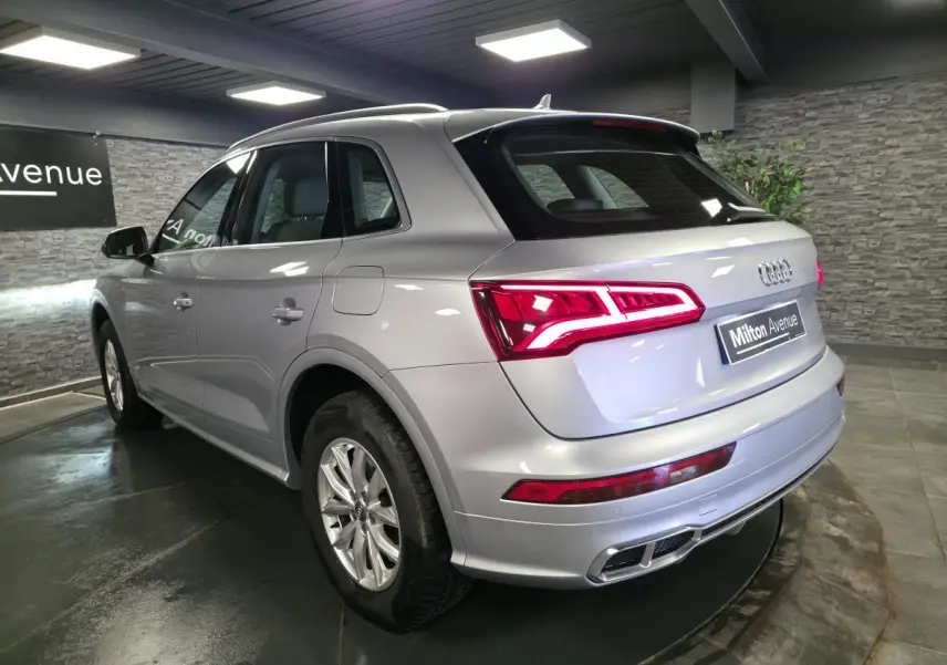 Audi Q5 gris en 3/4 arrière droit, avec feux LED allumés et jantes en aluminium 17 pouces.