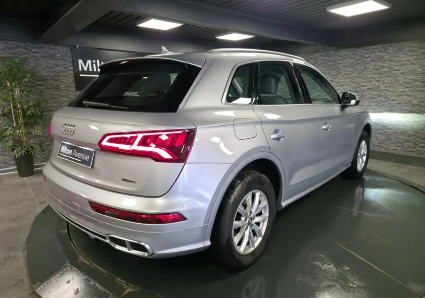 Audi Q5 hybride rechargeable gris, vue 3/4 arrière droit, feux arrière LED allumés et jantes 17 pouces.