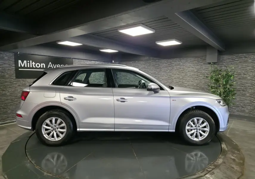 Audi Q5 gris en vue profil côté gauche, avec jantes en alliage et badge S line sur l'aile avant.