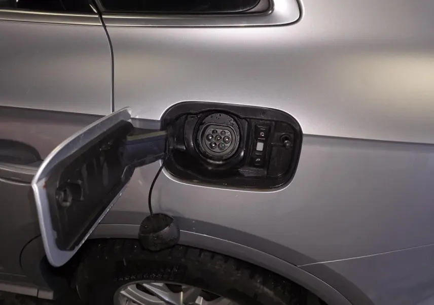 Détail de la trappe de recharge ouverte côté gauche sur Audi Q5 gris hybride rechargeable, avec prise visible.