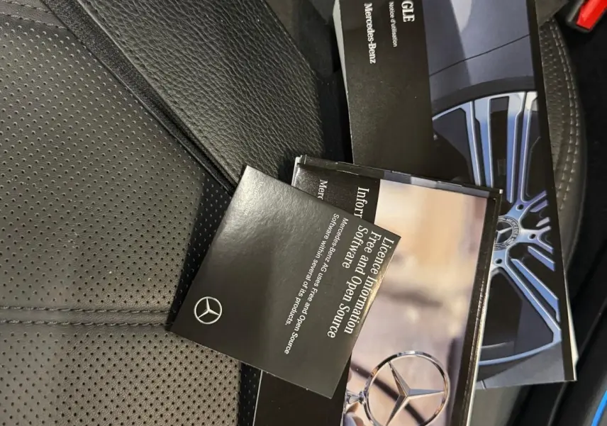 Vue intérieure du siège en cuir noir perforé avec plusieurs brochures Mercedes-Benz posées dessus.
