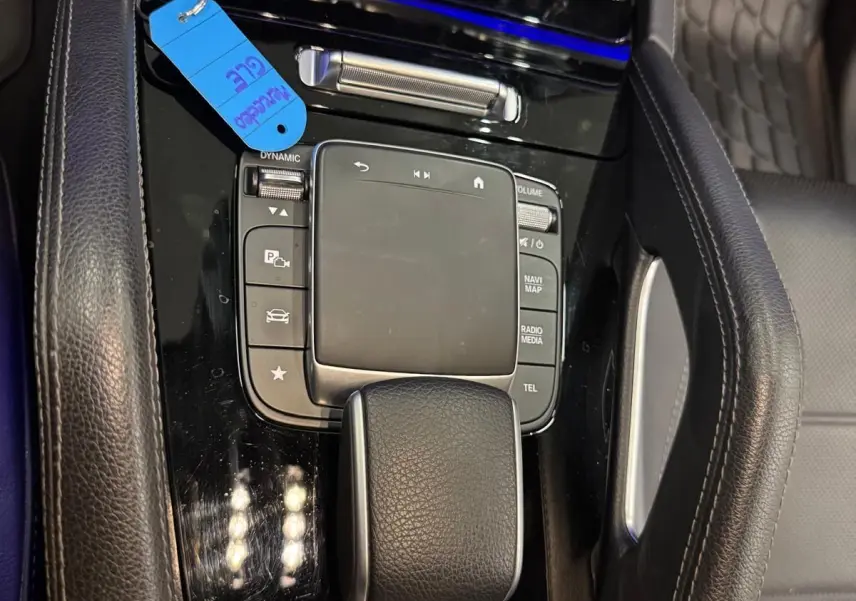 Vue rapprochée de la console centrale noire brillante du Mercedes GLE 400 E Hybrid AMG Line avec clé et cuir noir.
