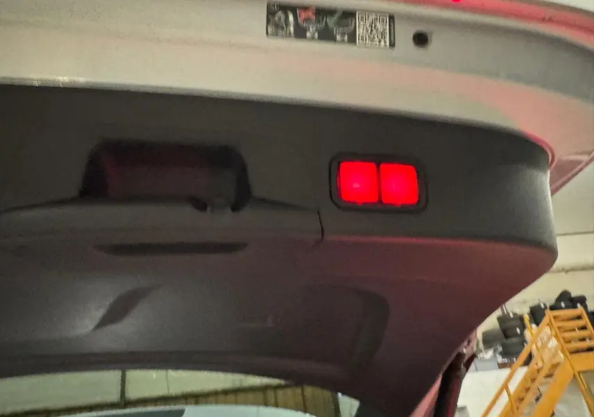 Vue en contre-plongée du hayon arrière ouvert d'un Mercedes GLE 400 E Hybrid AMG Line argent métallisé avec feux rouges intégrés.