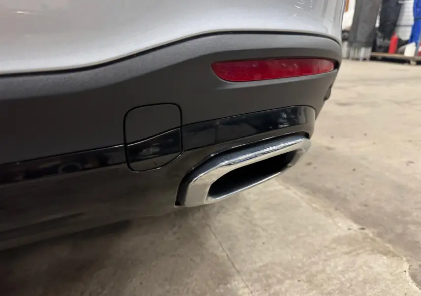 Gros plan sur la sortie d’échappement chromée arrière droite d’un Mercedes GLE 400 E Hybrid argent High-tech métallisé.