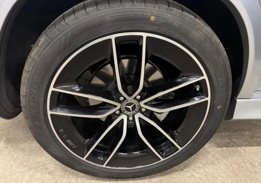 Gros plan sur la jante noire et argentée du Mercedes GLE 400 E Hybrid AMG Line, avec pneu Yokohama, côté droit argent High-tech.