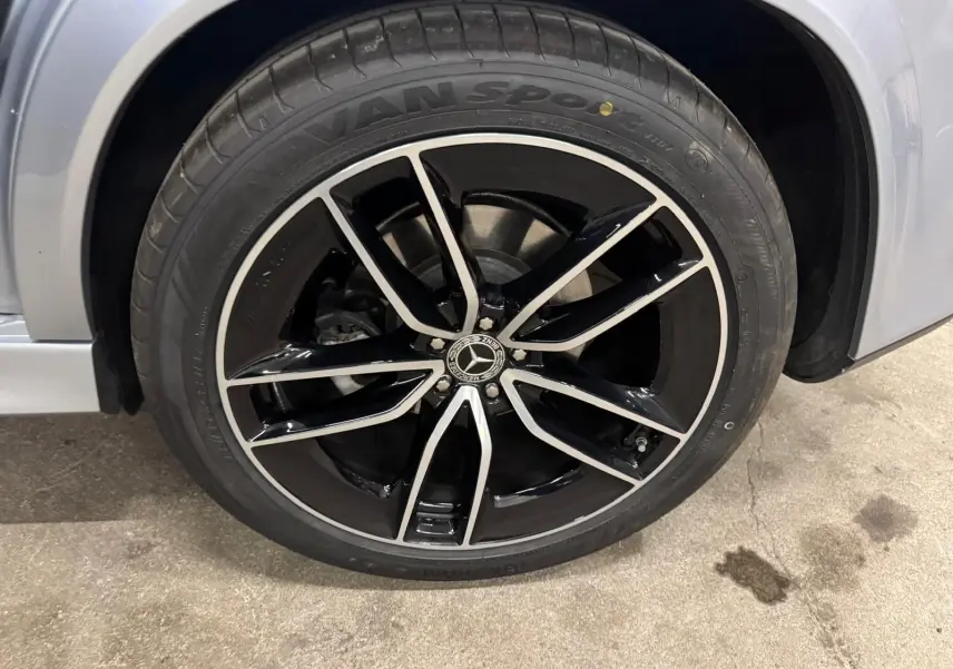Gros plan sur la roue avant droite argent High-tech métallisé du Mercedes GLE 400 E HYBRID AMG Line 2023 avec jante noire et argent.
