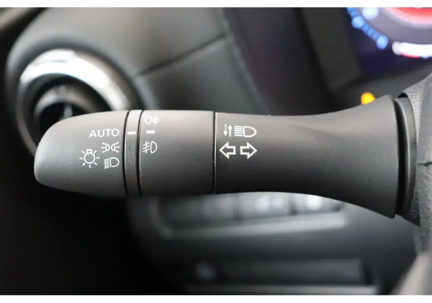 Gros plan sur la commande des feux et clignotants du Nissan Juke 2026, intérieur noir, détails des symboles lumineux.