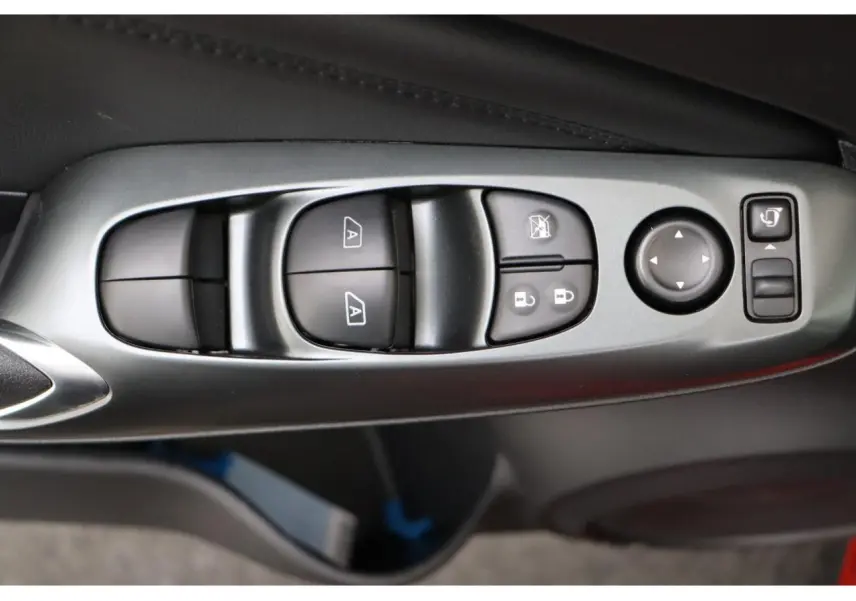 Gros plan sur les commandes de réglage des vitres et des rétroviseurs côté conducteur du Nissan Juke rouge Fuji Sunset.