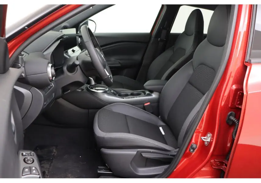 Vue intérieure côté conducteur du Nissan Juke rouge Fuji Sunset 2026, montrant sièges noirs et tableau de bord moderne.