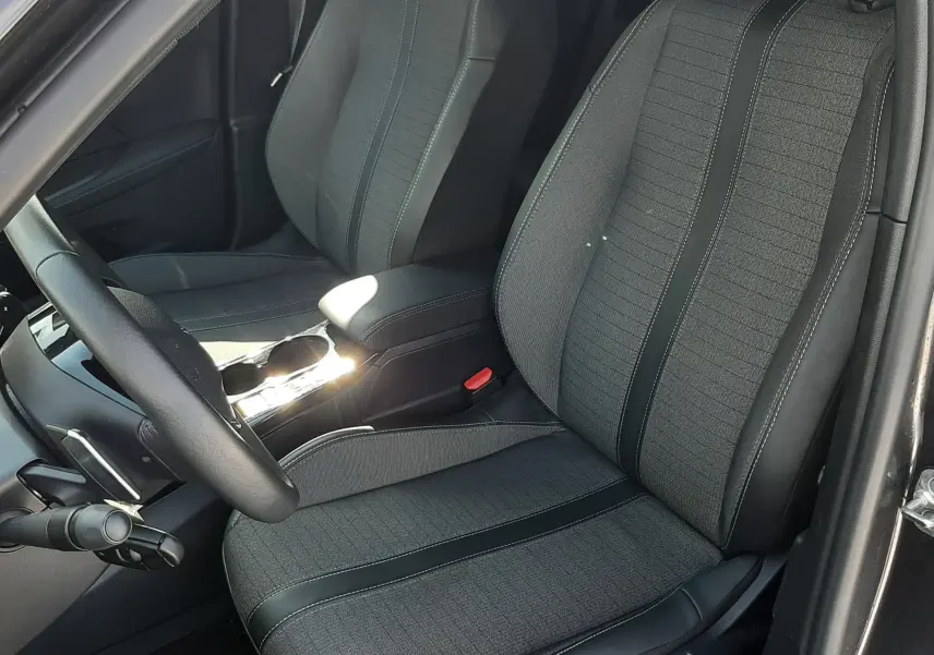 Vue intérieure côté conducteur du Peugeot 2008 2023 gris platinium, sièges tissu et cuir noir avec surpiqûres contrastées.