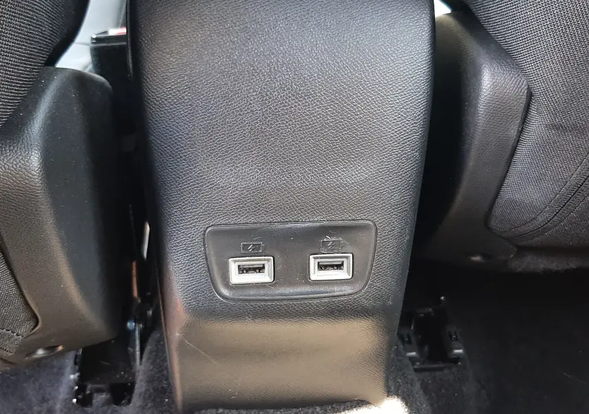 Prise USB double située à l'arrière de la console centrale d'un Peugeot 2008 gris platinium, intérieur noir.