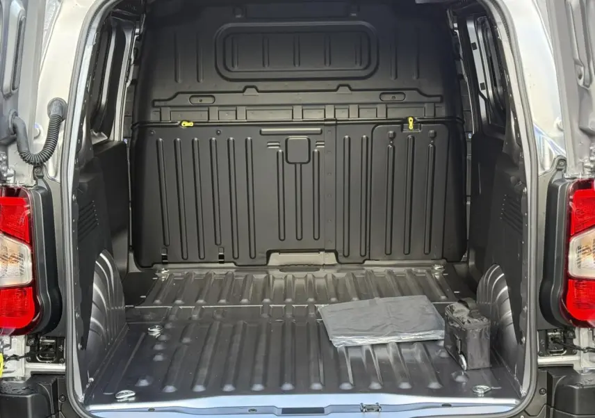 Vue arrière ouverte du Citroën Berlingo gris Artense montrant l'espace de chargement tôlé et vide avec deux petits objets au sol.