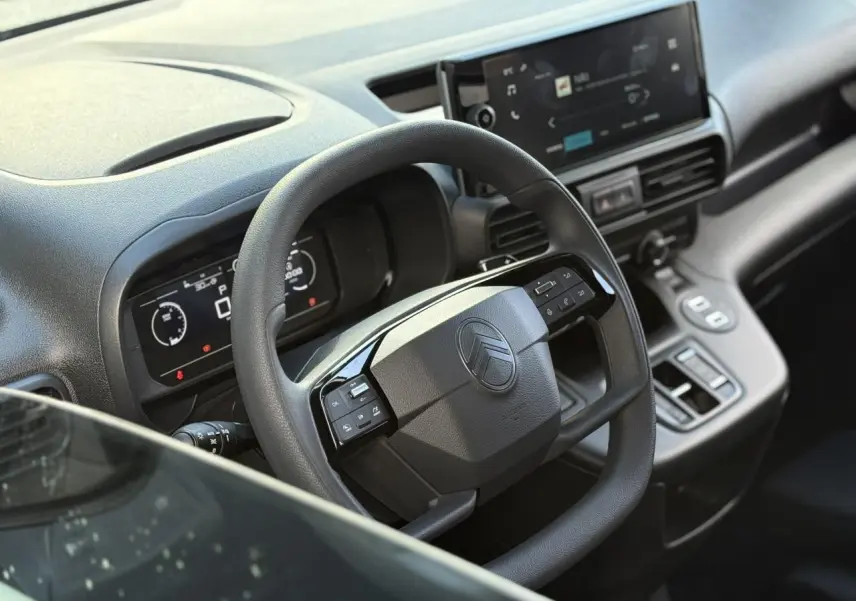 Vue rapprochée du volant multifonctions et tableau de bord numérique du Citroën Berlingo 2025 gris Artense.