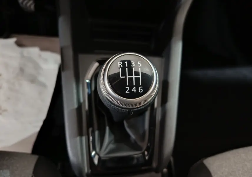 Le levier de vitesses manuel noir de la Renault Clio gris clair, vu en gros plan depuis le dessus.