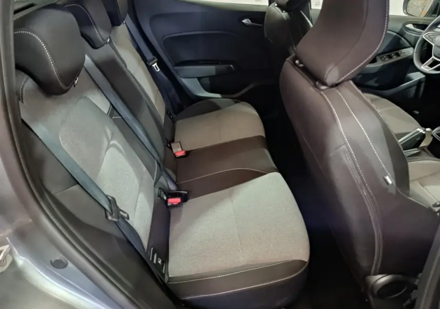 Vue intérieure arrière droite de la Renault Clio gris clair, montrant les sièges tissu bicolores et ceintures de sécurité.