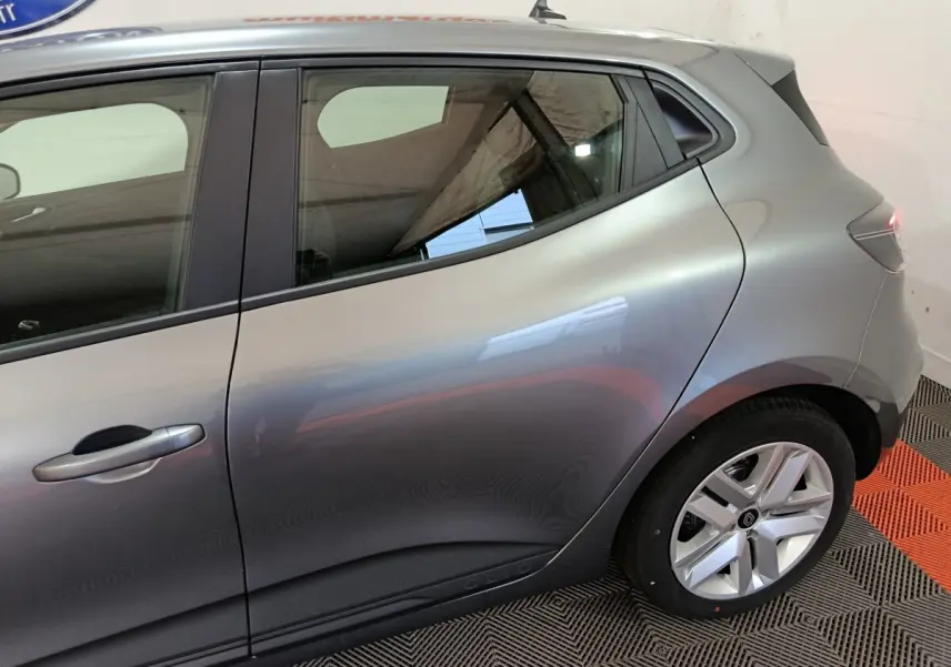 Vue latérale droite sur l'arrière d'une Renault Clio gris clair, mettant en valeur la ligne fluide et la jante alliage.