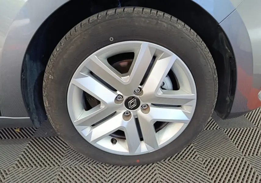 Gros plan sur la roue avant gauche de la Renault Clio gris clair, mettant en valeur la jante alliage à design moderne.