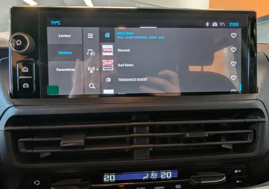 Écran tactile central du tableau de bord du Citroën Jumpy gris titane, affichant les stations radio avec commandes climatisation en dessous.