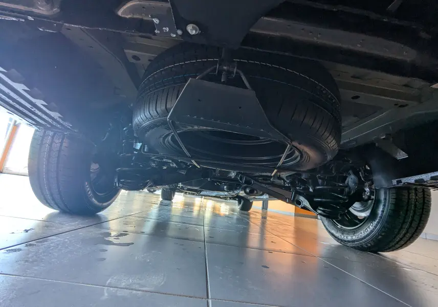 Vue en contre-plongée sous le Citroën Jumpy cabine approfondie gris titane, montrant la roue de secours et le train arrière.