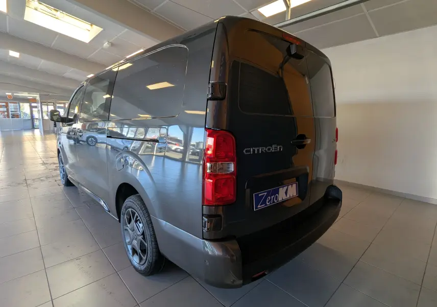 Vue 3/4 arrière droit du Citroën Jumpy Cabine Approfondie gris titane 2026 en intérieur, avec feux arrière rouges visibles.