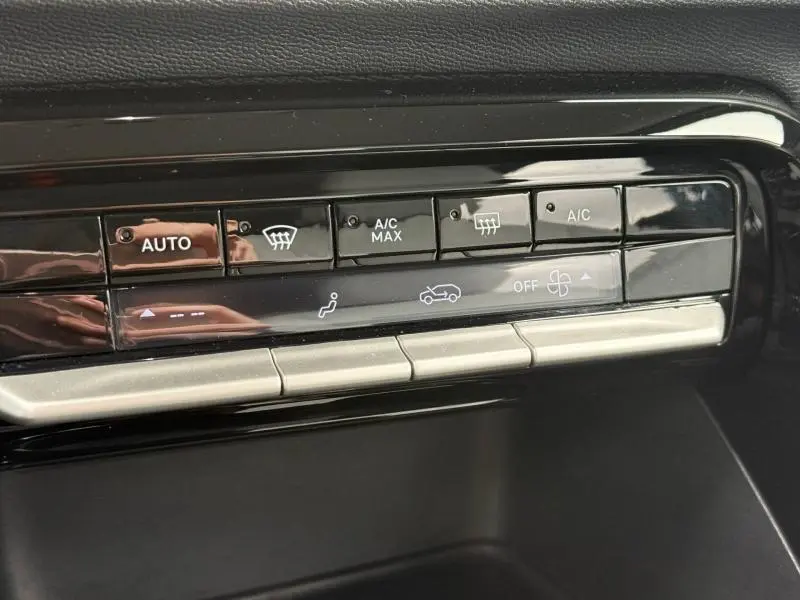 Détail du panneau de commande de climatisation avec boutons tactiles noirs et finition argentée dans la Citroën C3 électrique gris Mercury 2025.