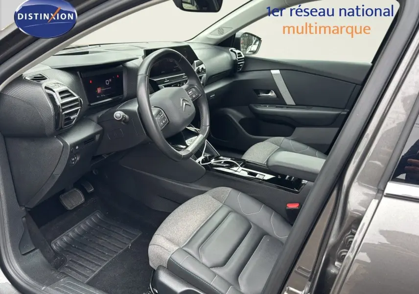 Vue intérieure côté conducteur de la Citroën C4 gris 2021, avec sièges bi-matière cuir et tissu et tableau de bord moderne.