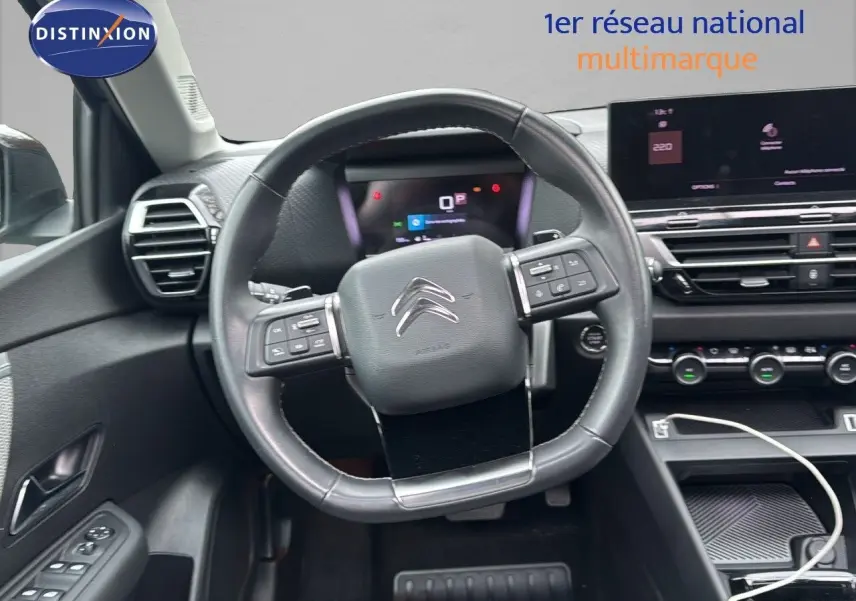 Vue intérieure centrée sur le volant cuir noir et le tableau de bord numérique d'une Citroën C4 gris 2021.
