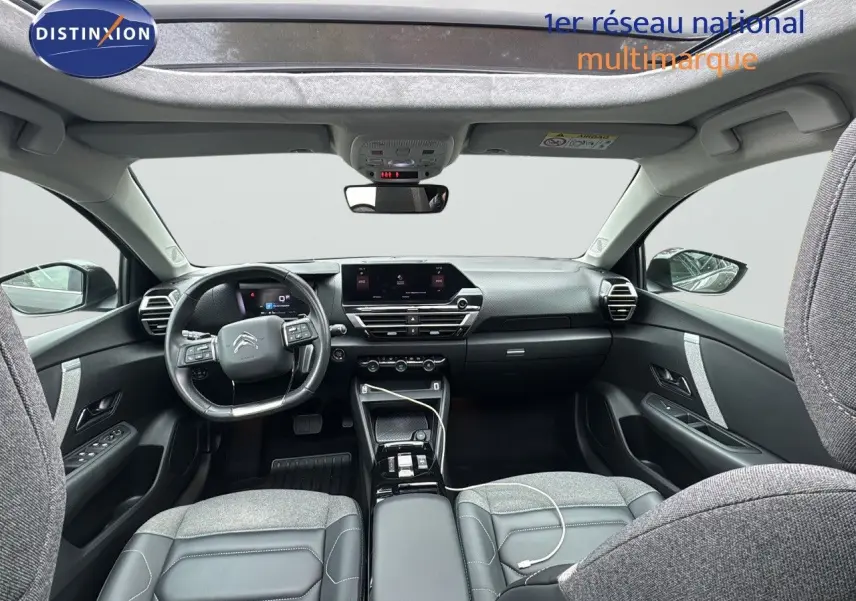 Vue intérieure avant de la Citroën C4 2021, tableau de bord moderne avec écran tactile et sièges gris tissu et cuir.