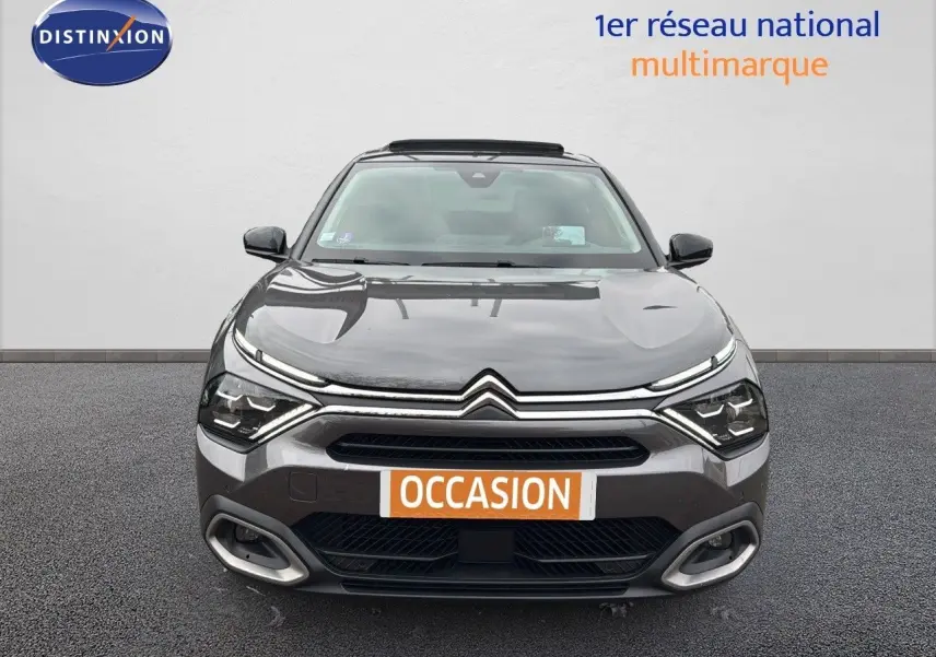 Vue frontale d'une Citroën C4 gris métallisé avec phares LED et calandre distinctive, sur fond neutre.